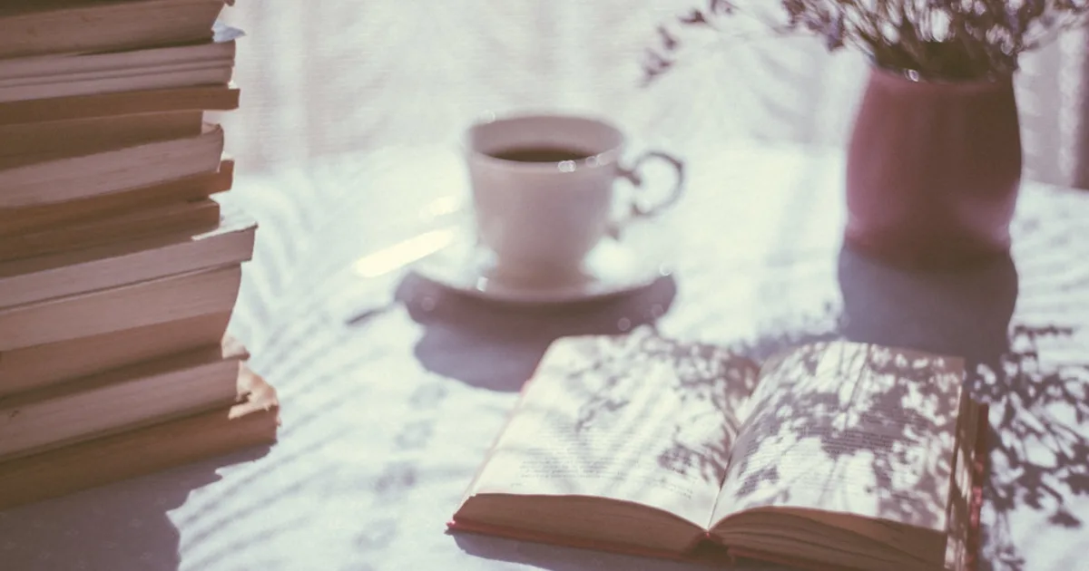 A stack of books beside a cup of coffee, a starting shelf for new readers.