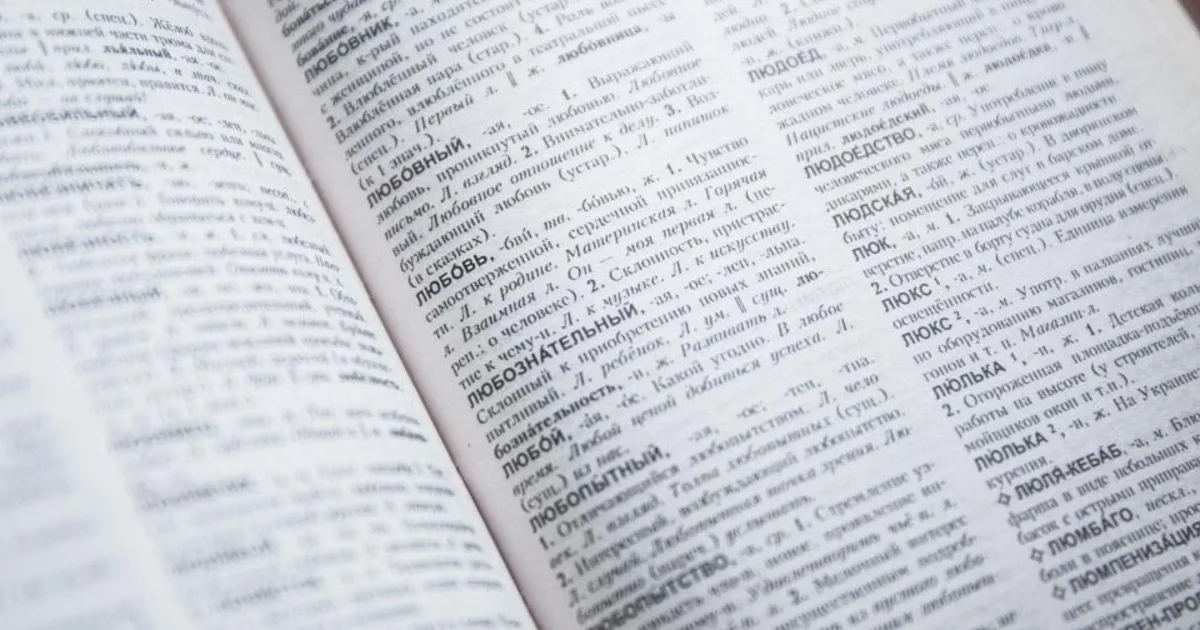 An open book and dictionary on a desk, evoking the work of translation.